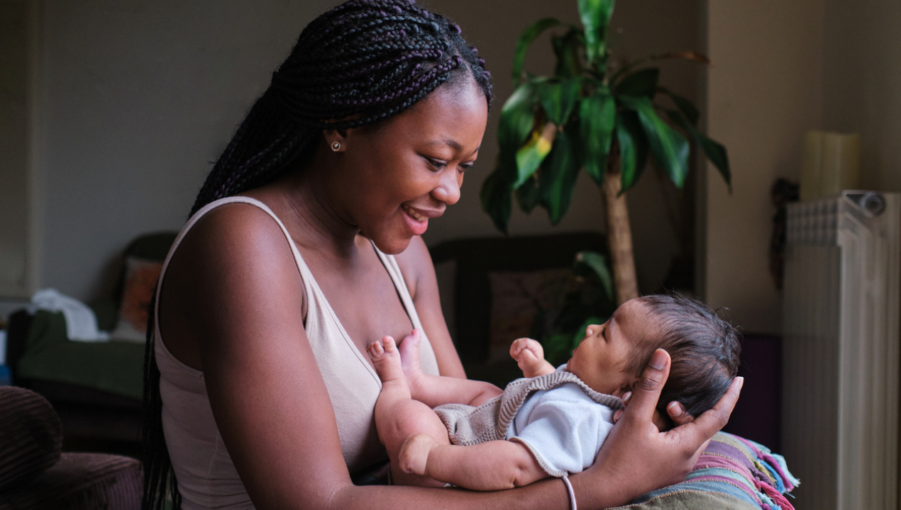 woman smiles and cradles her baby