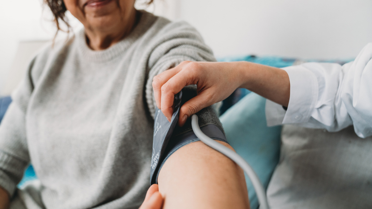 Woman has her blood pressure checked by cuff by physician