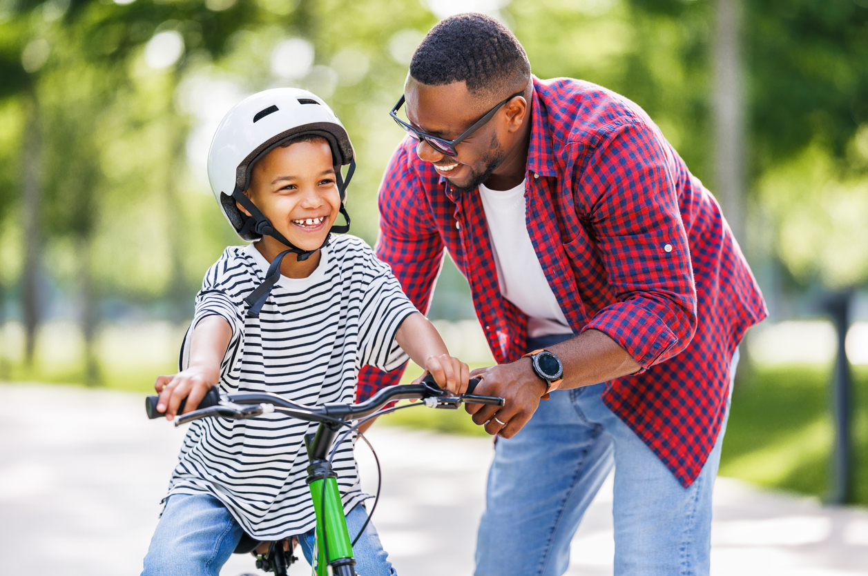 Man helps his son learn how to ride a bike