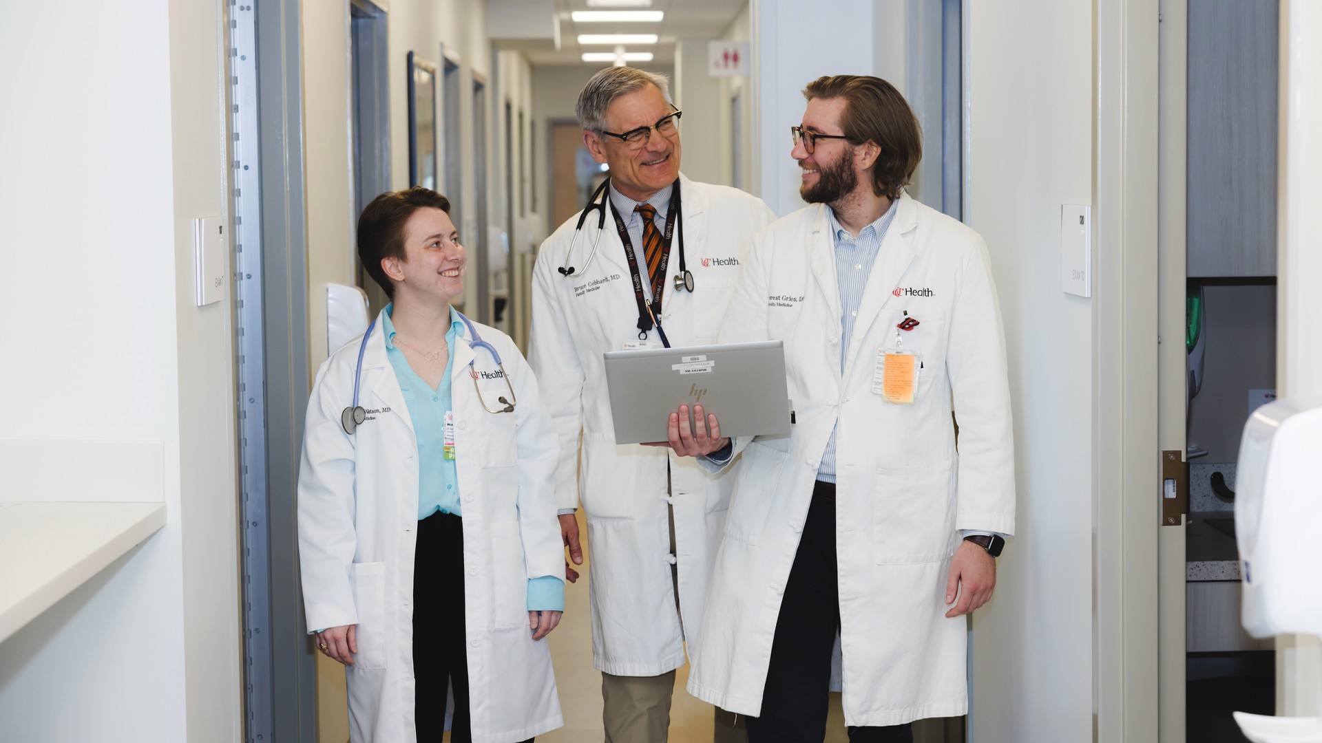 Three medical providers walk through a hallway in a medical setting.