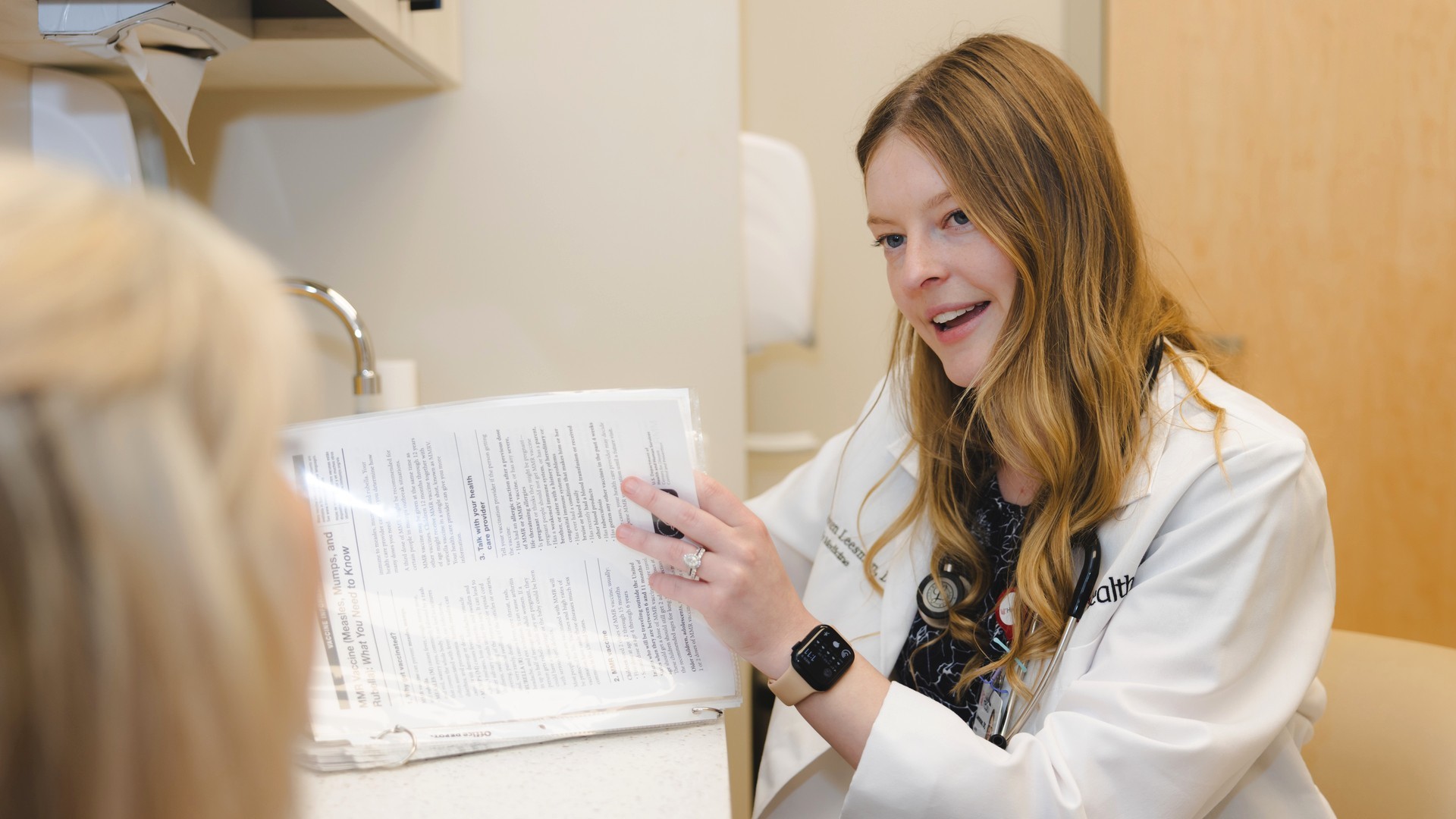 A primary care provider talks with a patient in a medical setting. 