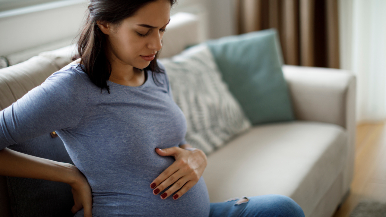 Pregnant woman sitting on the couch with back pain