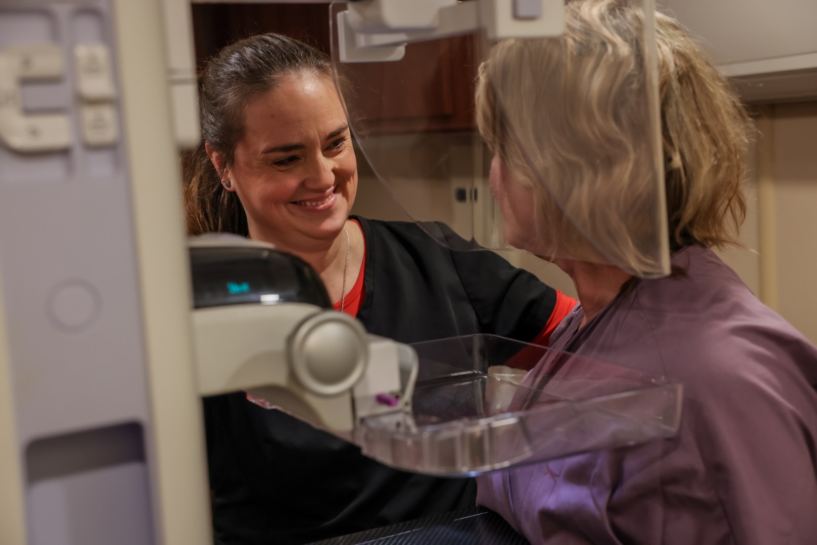 UC Health imaging technician assists a patient during a mammogram