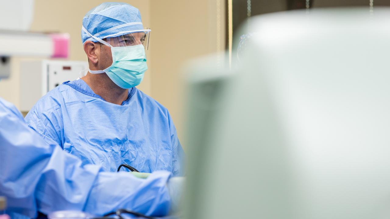 Physicians in scrubs and masks perform a medical procedure. 