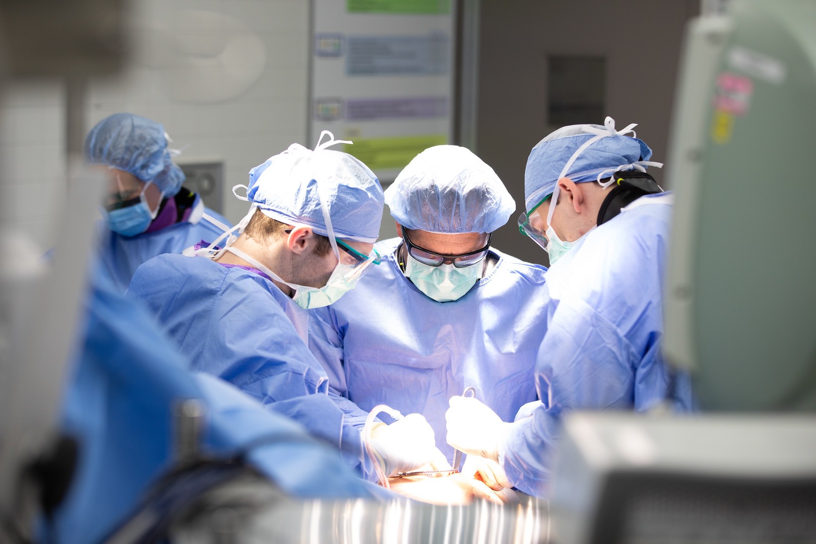 Physicians in scrubs and masks perform a medical procedure. 