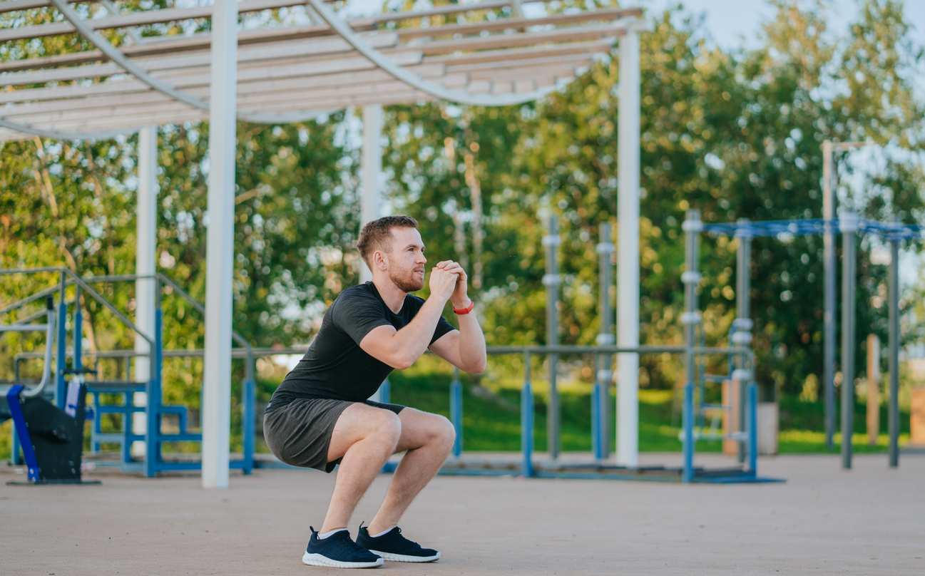Man does squats in a park setting