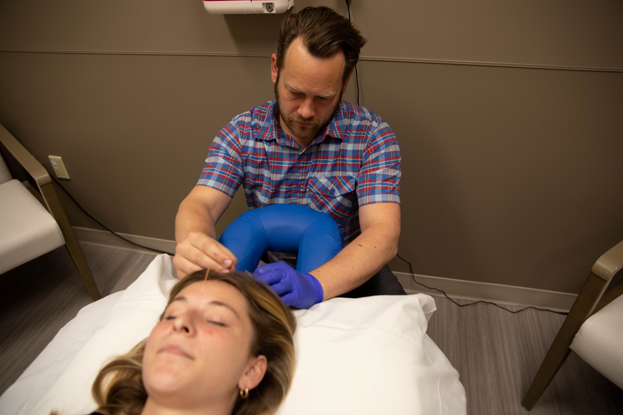 A therapist helps a patient with acupuncture.