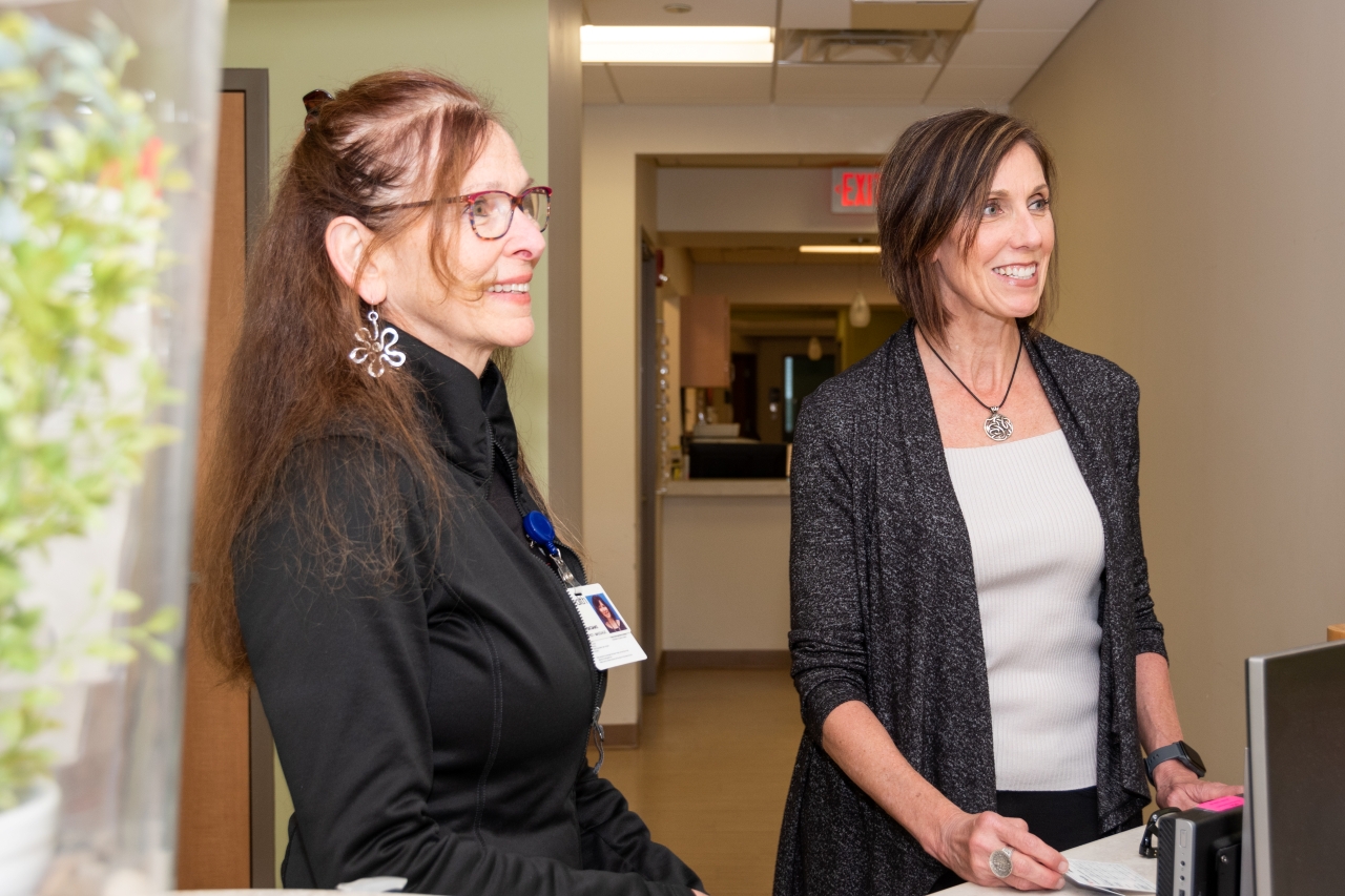 Two women in a hallway talking with someone out of frame.
