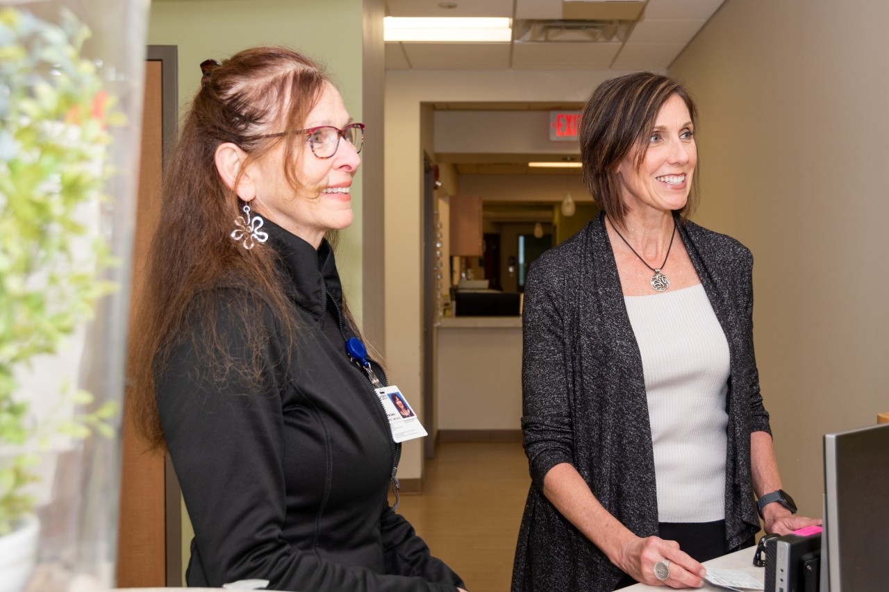 Two women in a hallway talking with someone out of frame.