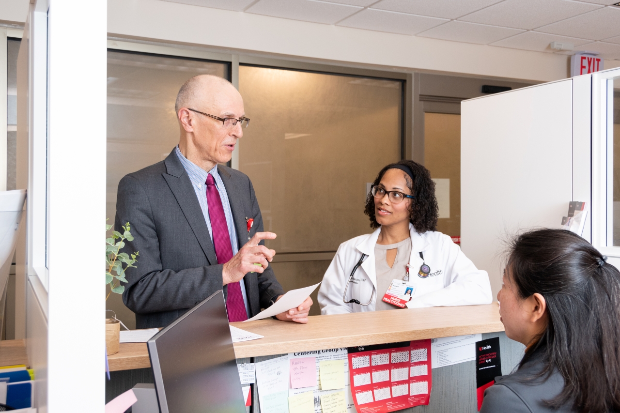 Medical providers talk while standing next to a desk.