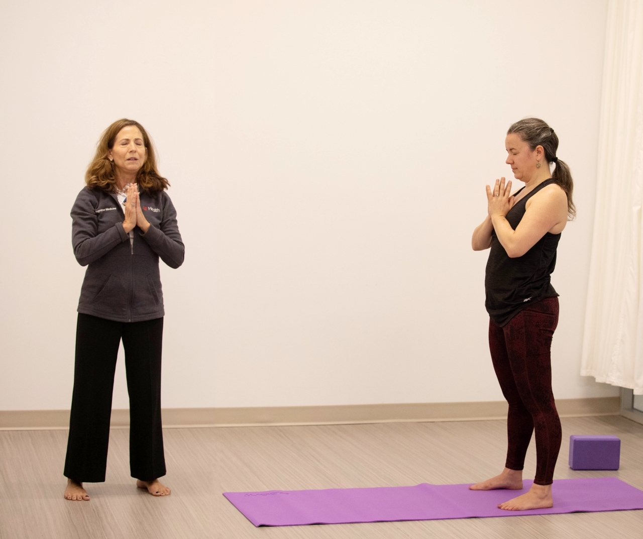Therapist leads a yoga session for a participant. 