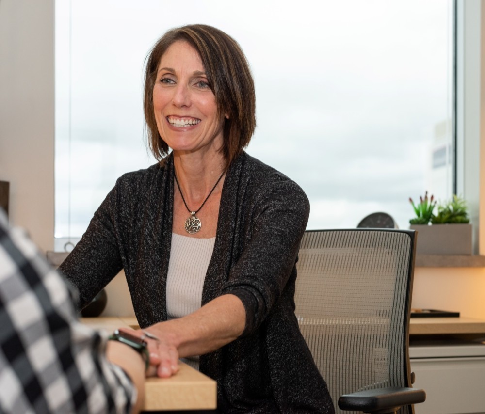 A medical provider smiles and touches the hand of a patient. 