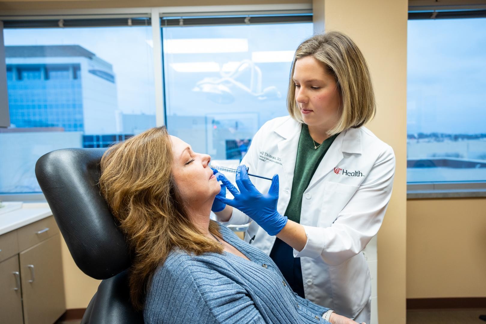 Dr. Thomas performs facial procedure on a patient in medical office