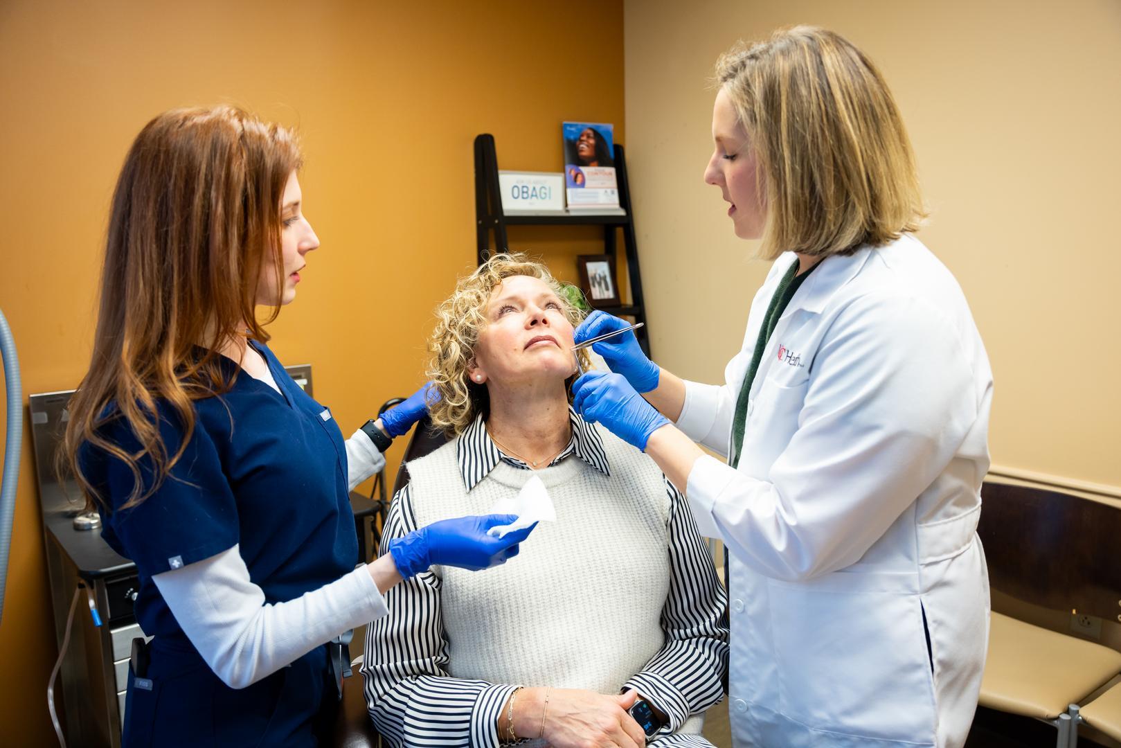 Three medical personnel walk through a sunlit hallway.