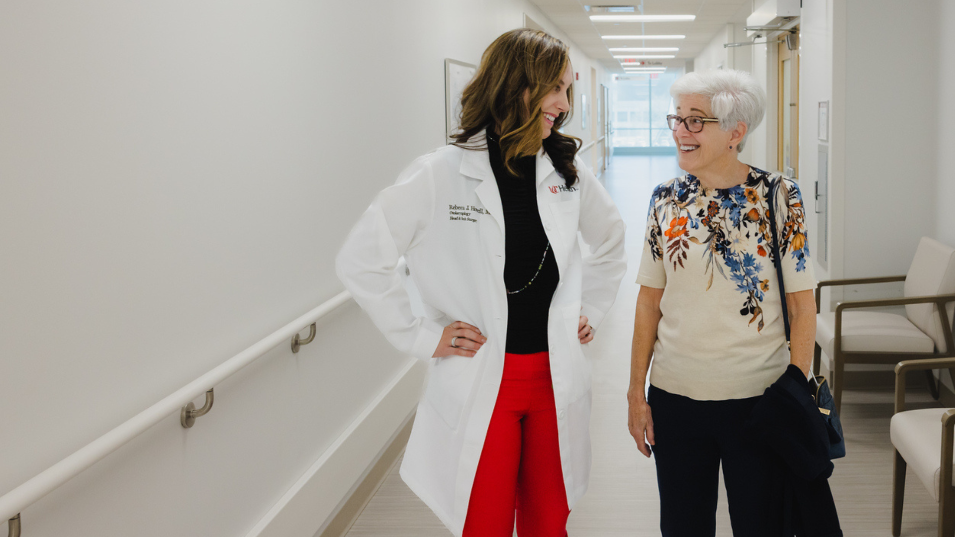 Patient and physician walk down a hall in medical setting