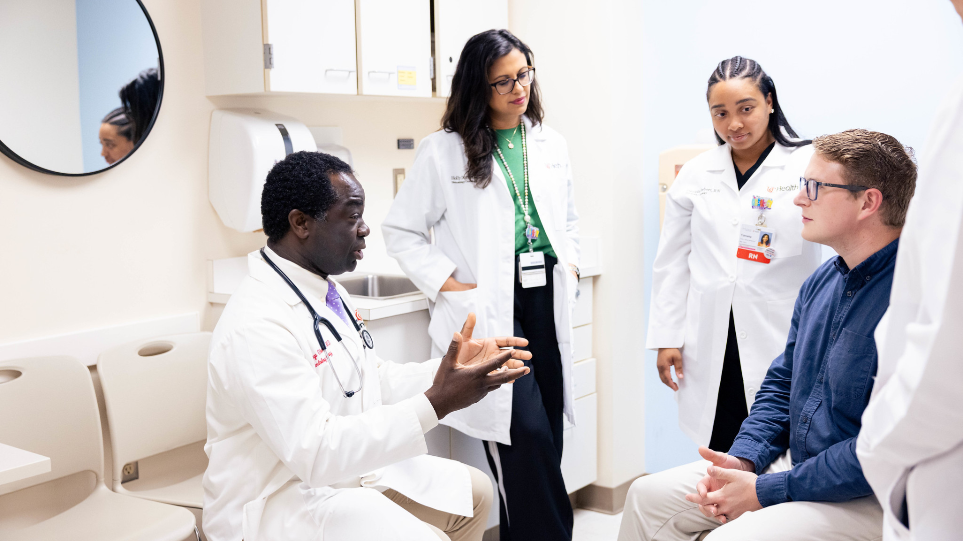 Care team at UC Health meets with patient in an exam room.