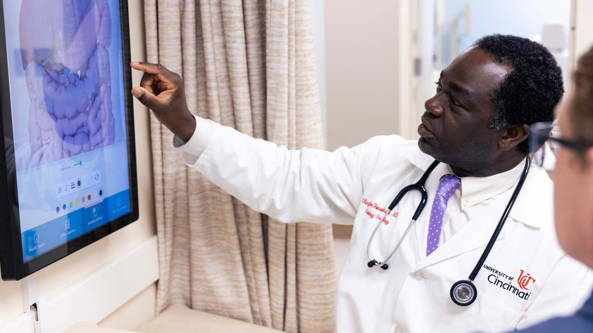 Doctor holds hand toward image on screen.