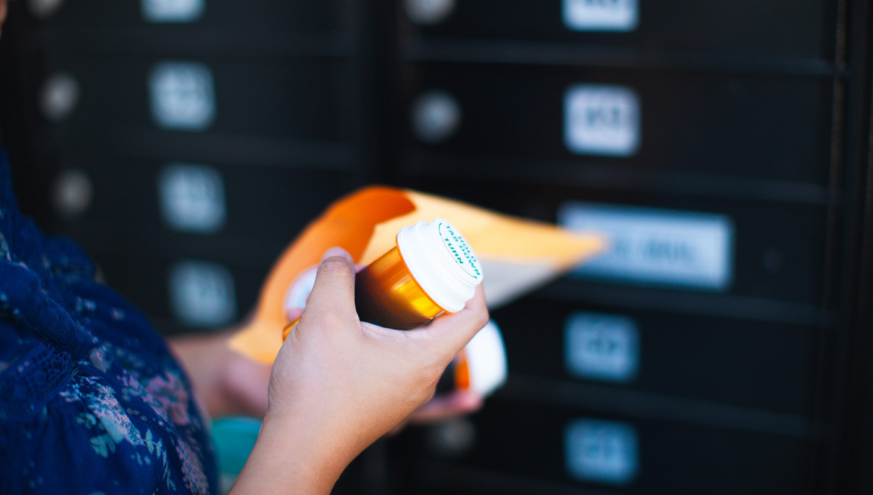 Woman opens an envelope with her prescriped medication bottles from her mailbox