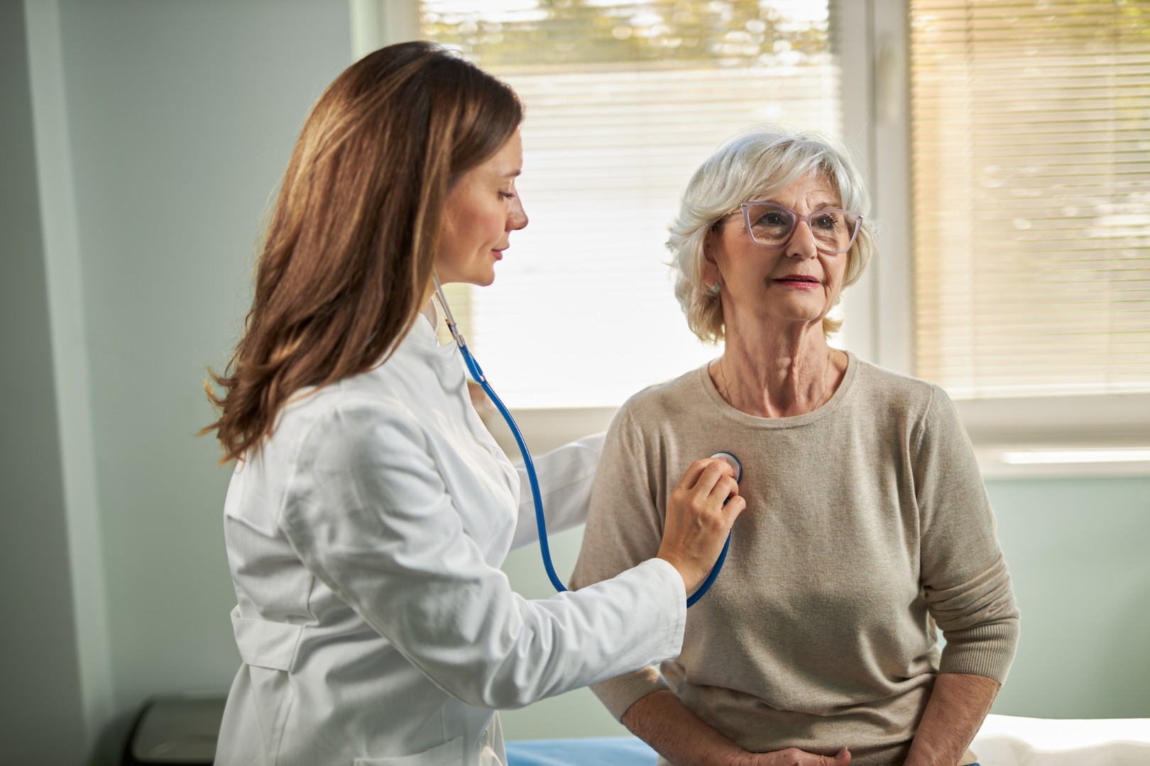 A doctor listening to a patient's lungs in the clinic.