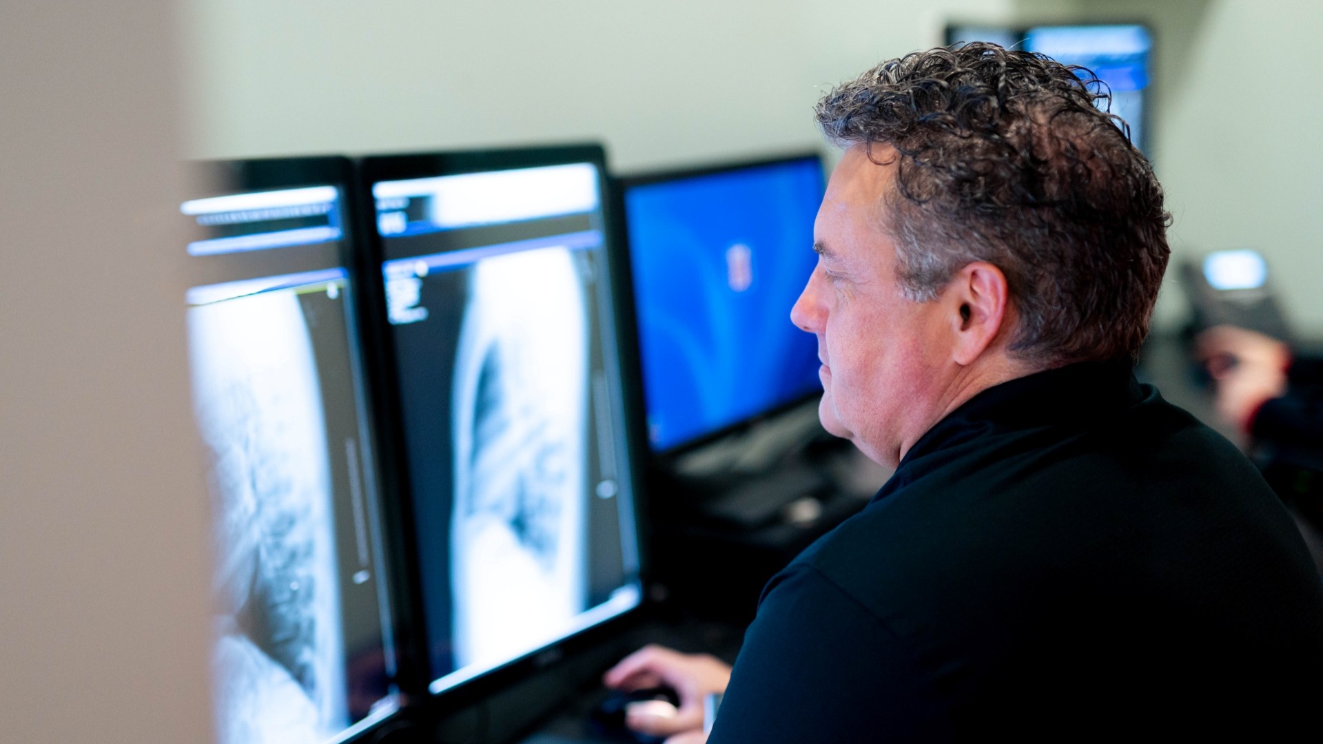 A medical technician studies an image on a computer monitor. 
