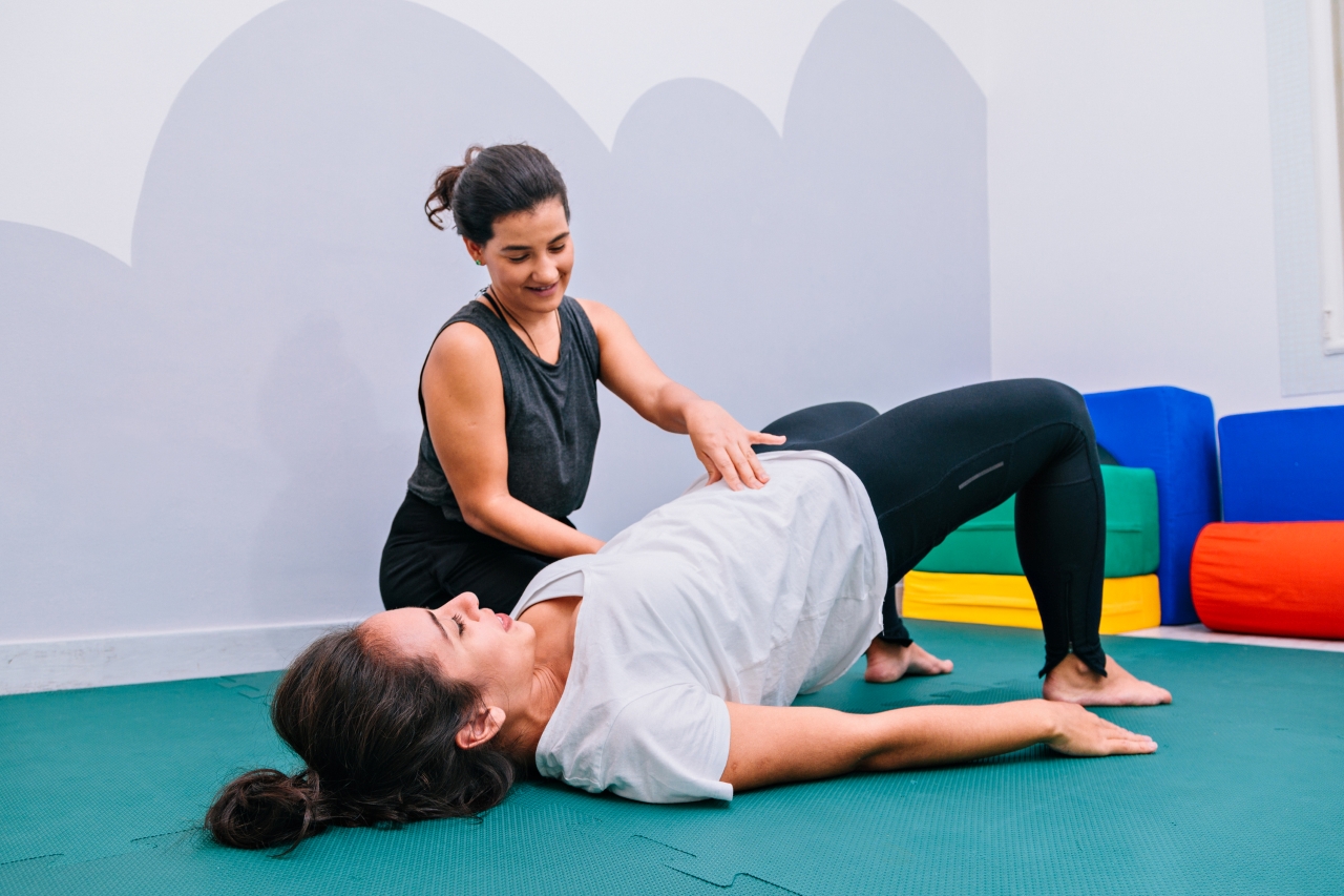 Woman exercises with a therapist assisting to the side. 