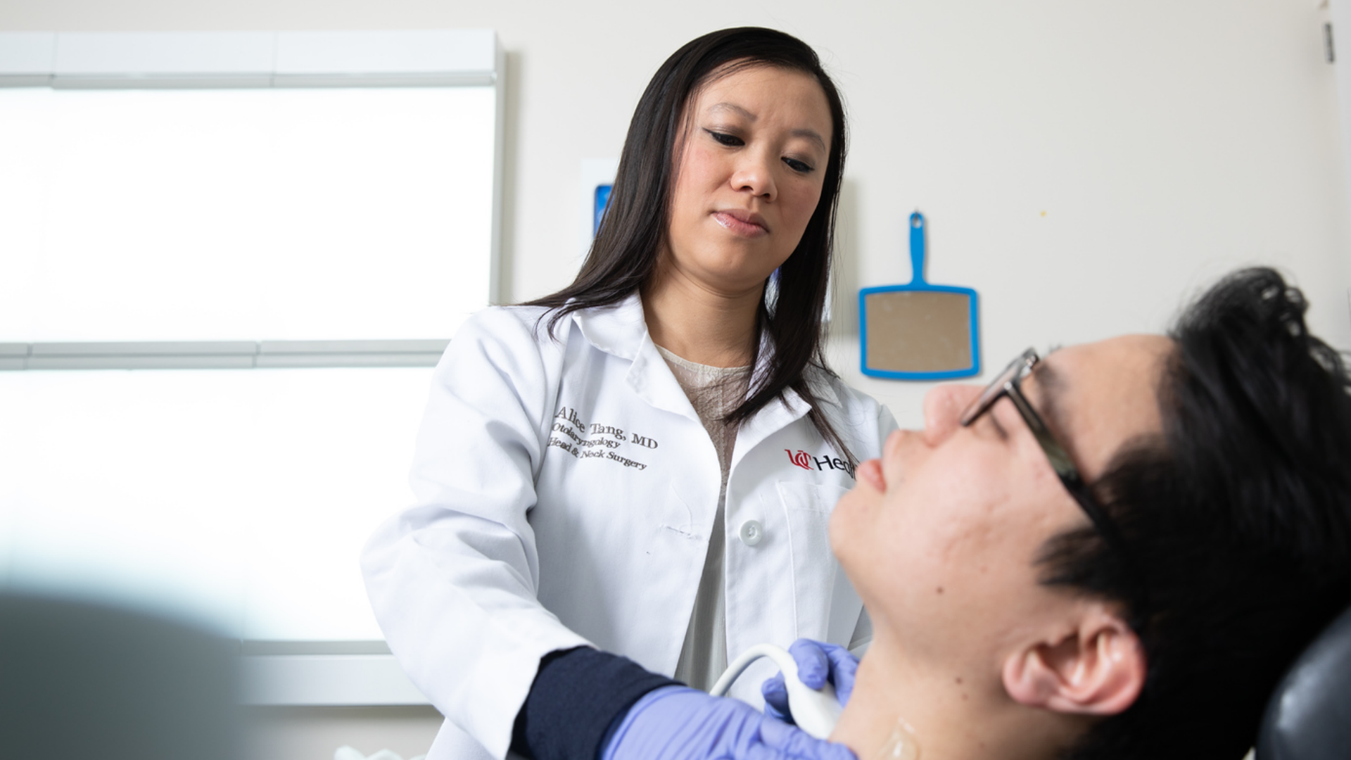 Dr. Tang examines patient's neck during visit