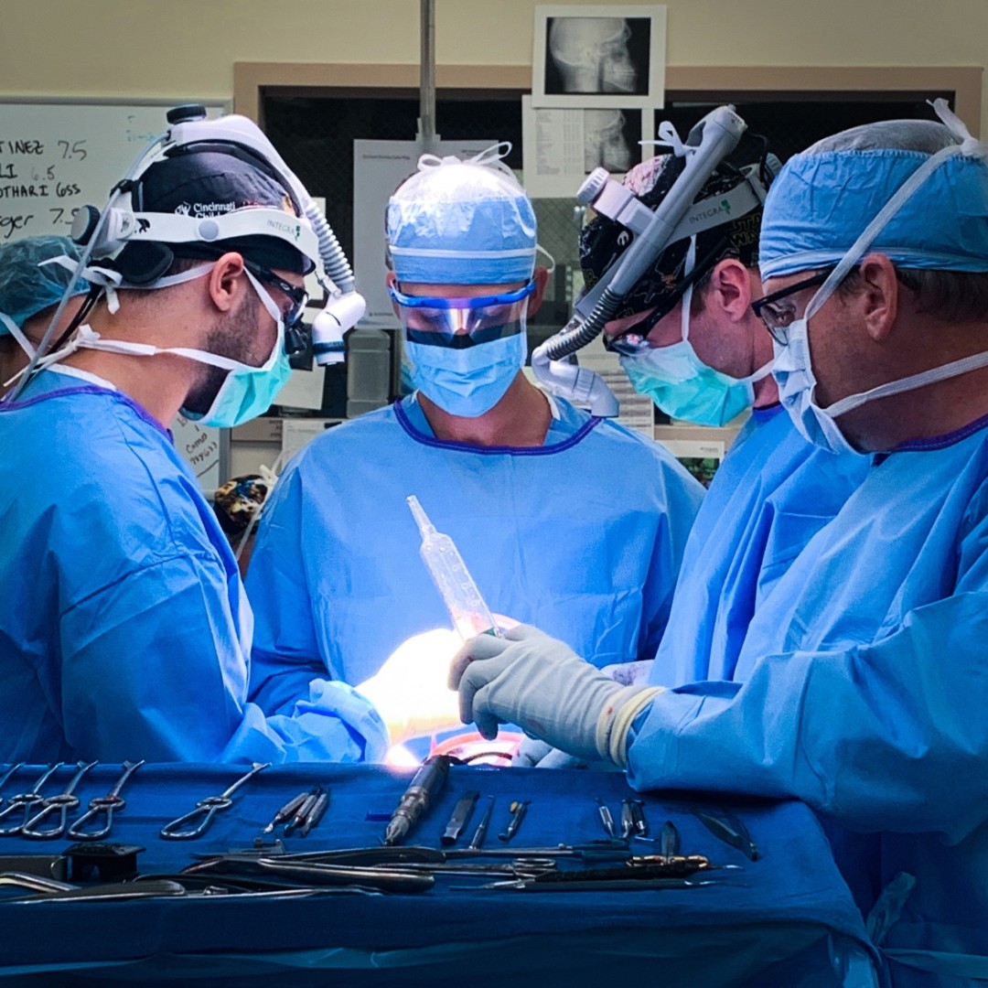 Physicians in scrubs and masks perform a medical procedure. 