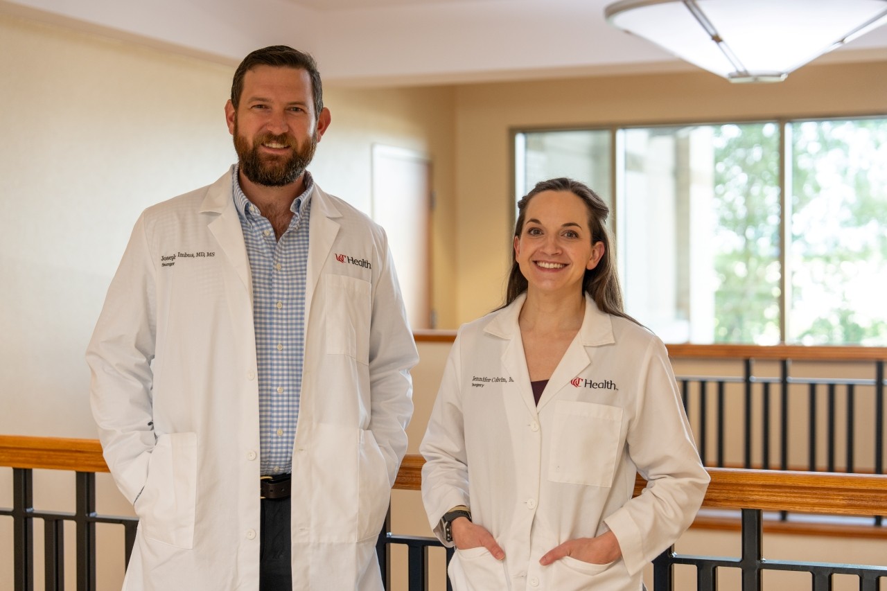 Physicians stand in a medical environment and smile for the camera.
