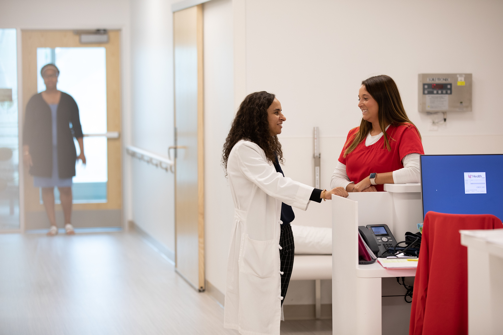 Transplant doctor speaking with nurse at unit station.