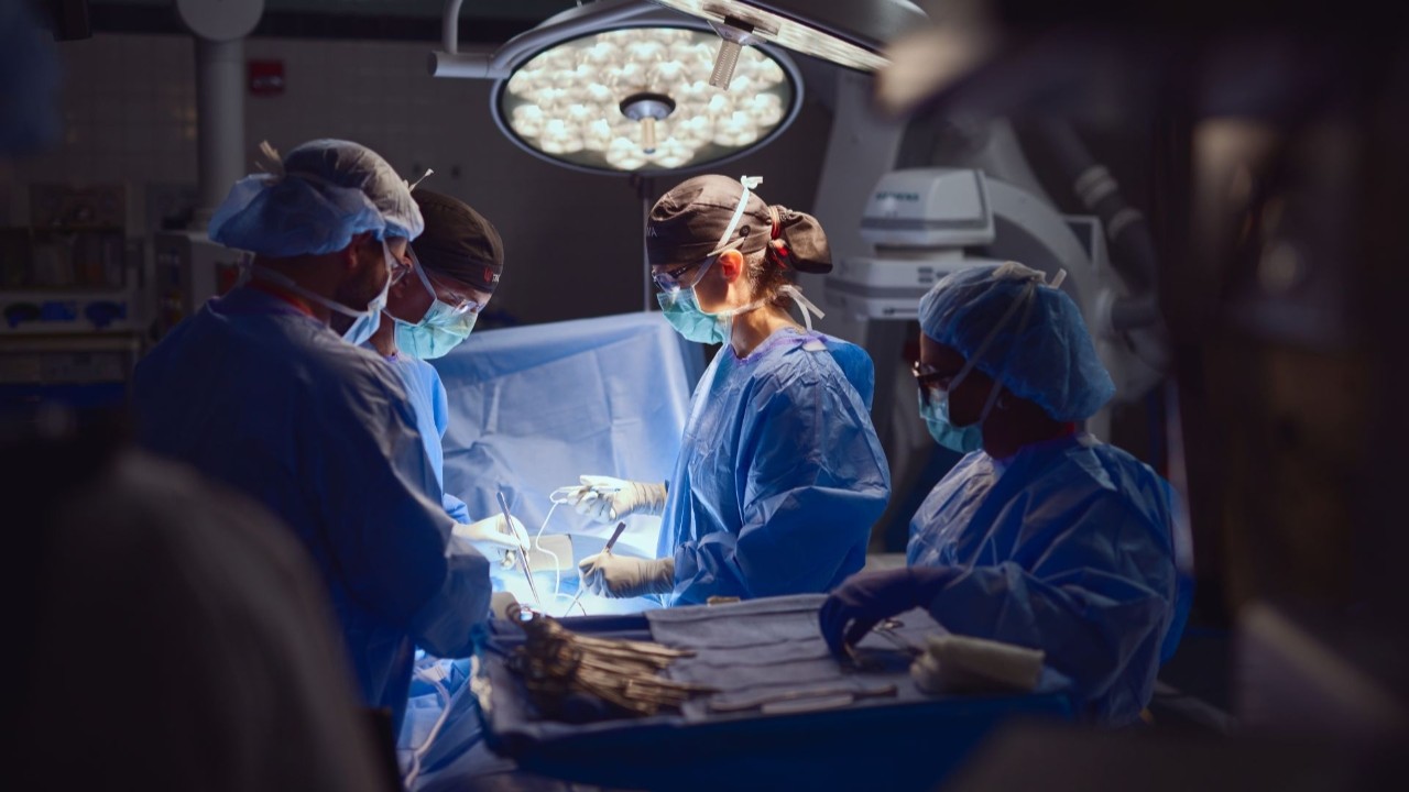 Physicians in scrubs and masks perform surgery in the OR. 