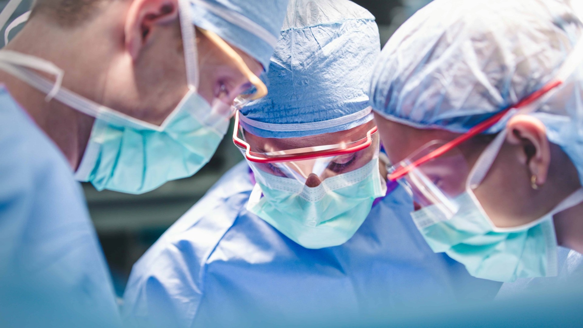 Team of three doctors in scrubs performing a surgery in our UCMC Level I Trauma Center.