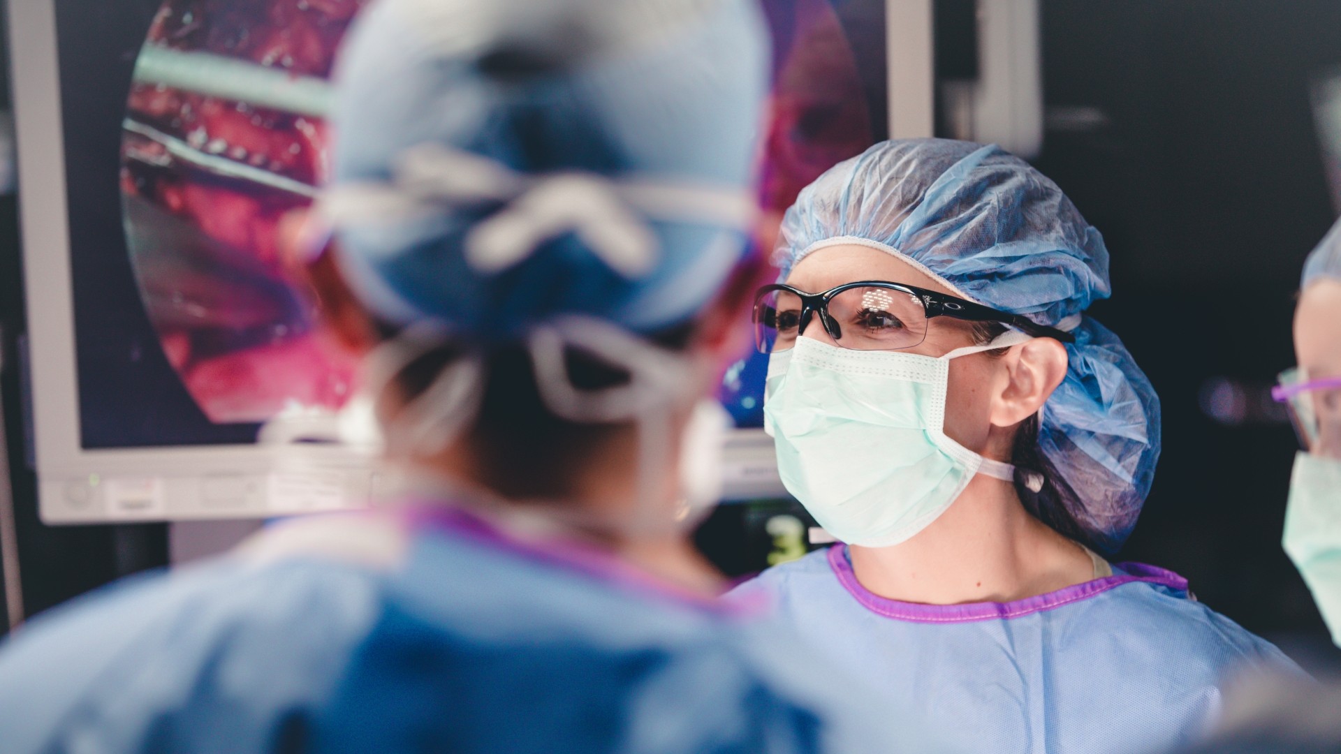 Dr. Makely in mask and scrubs post a medical procedure looking in the distance.