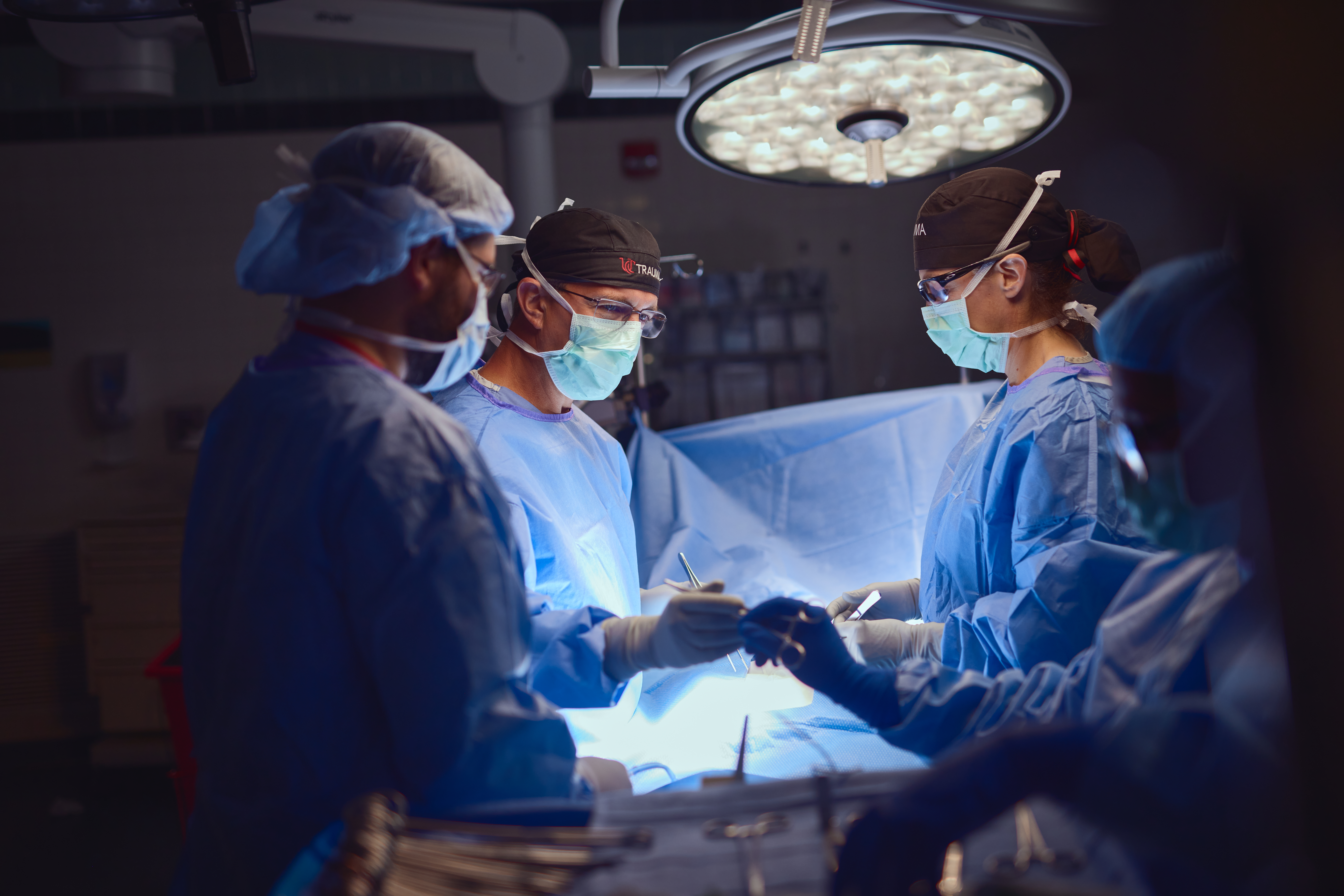 Physician in scrubs and masks perform surgery. 
