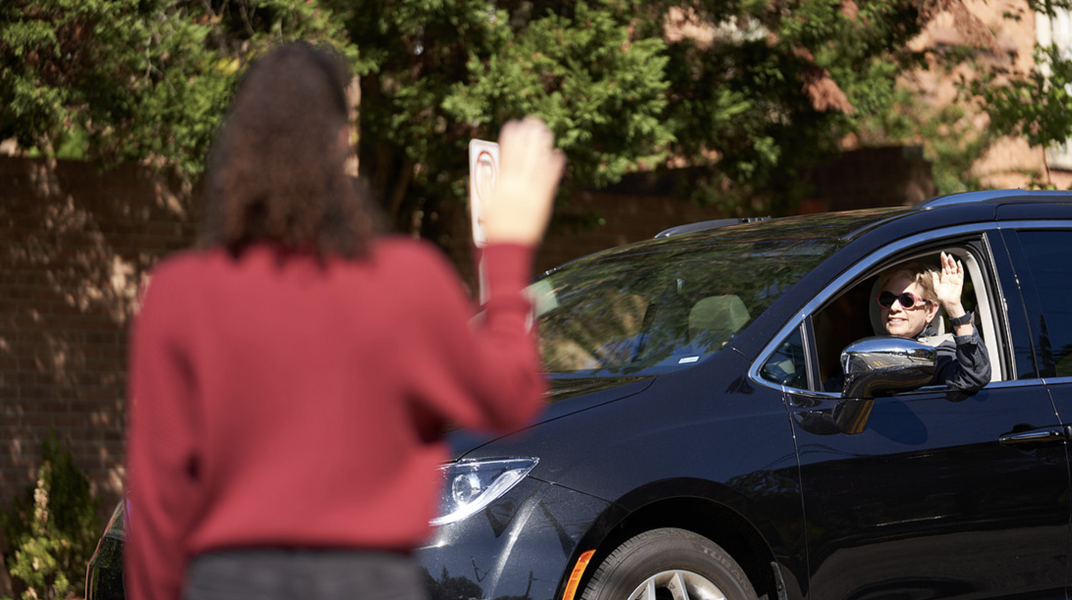 Safe driver waving a pedestrian across the street. 