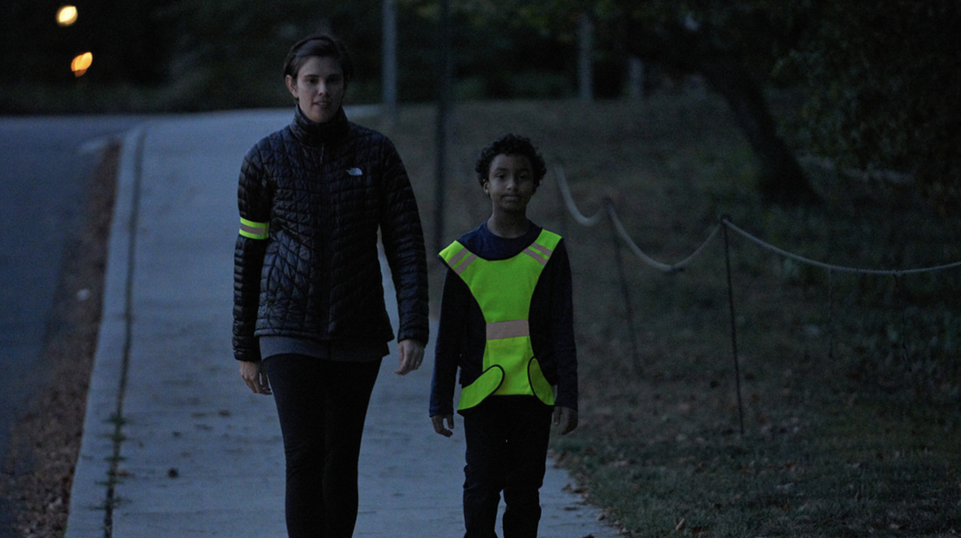 Safe walkers on a sidewalk wearing reflective gear.