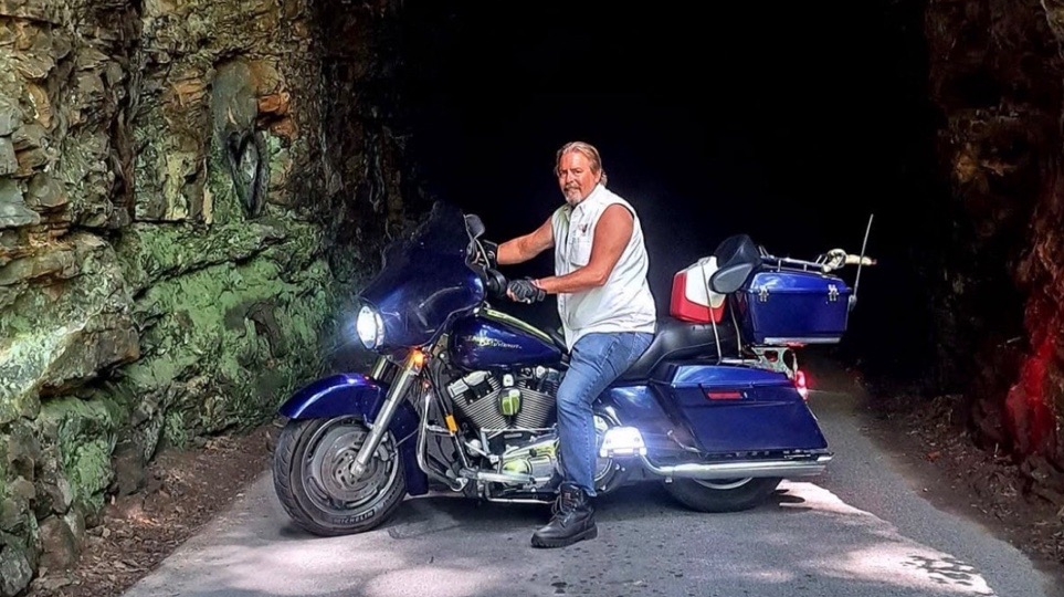Chris Aldred posing on his motorcycle in front of a cave prior to his injuries.