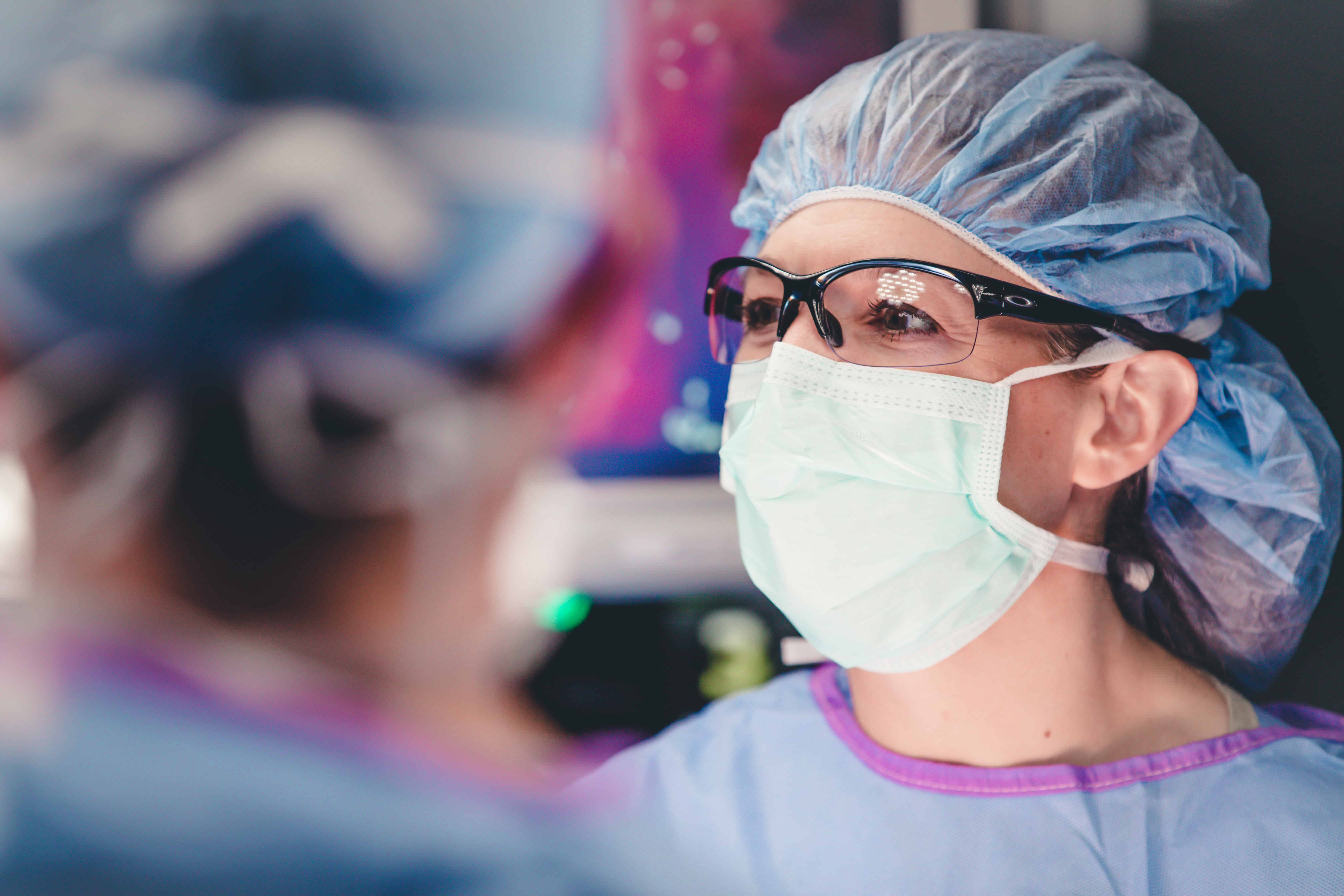 Dr. Makely in mask and scrubs post a medical procedure looking in the distance.