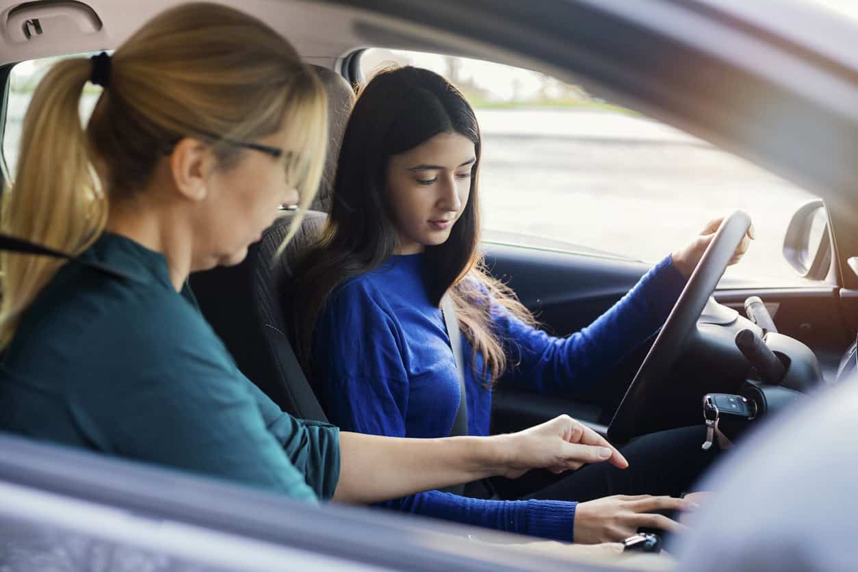 A teen and parent practicing driving safety behind the wheel.