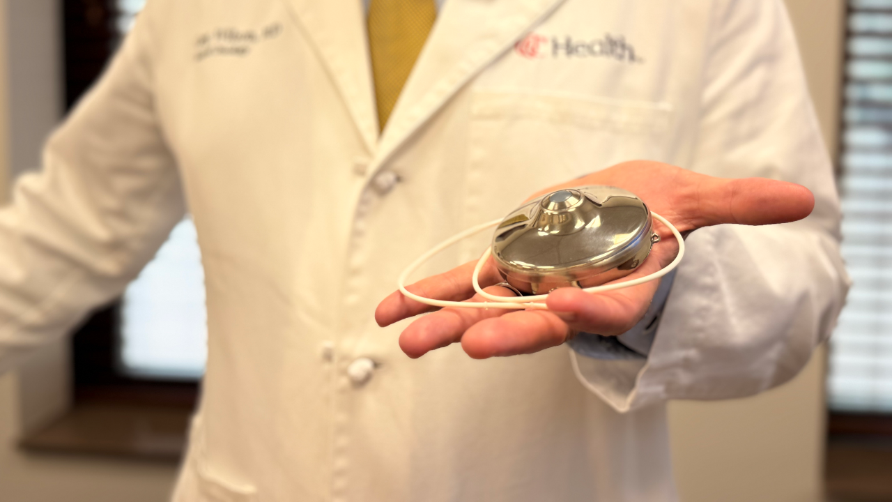 UC Health surgeon holds an HAI pump in the palm of his hand
