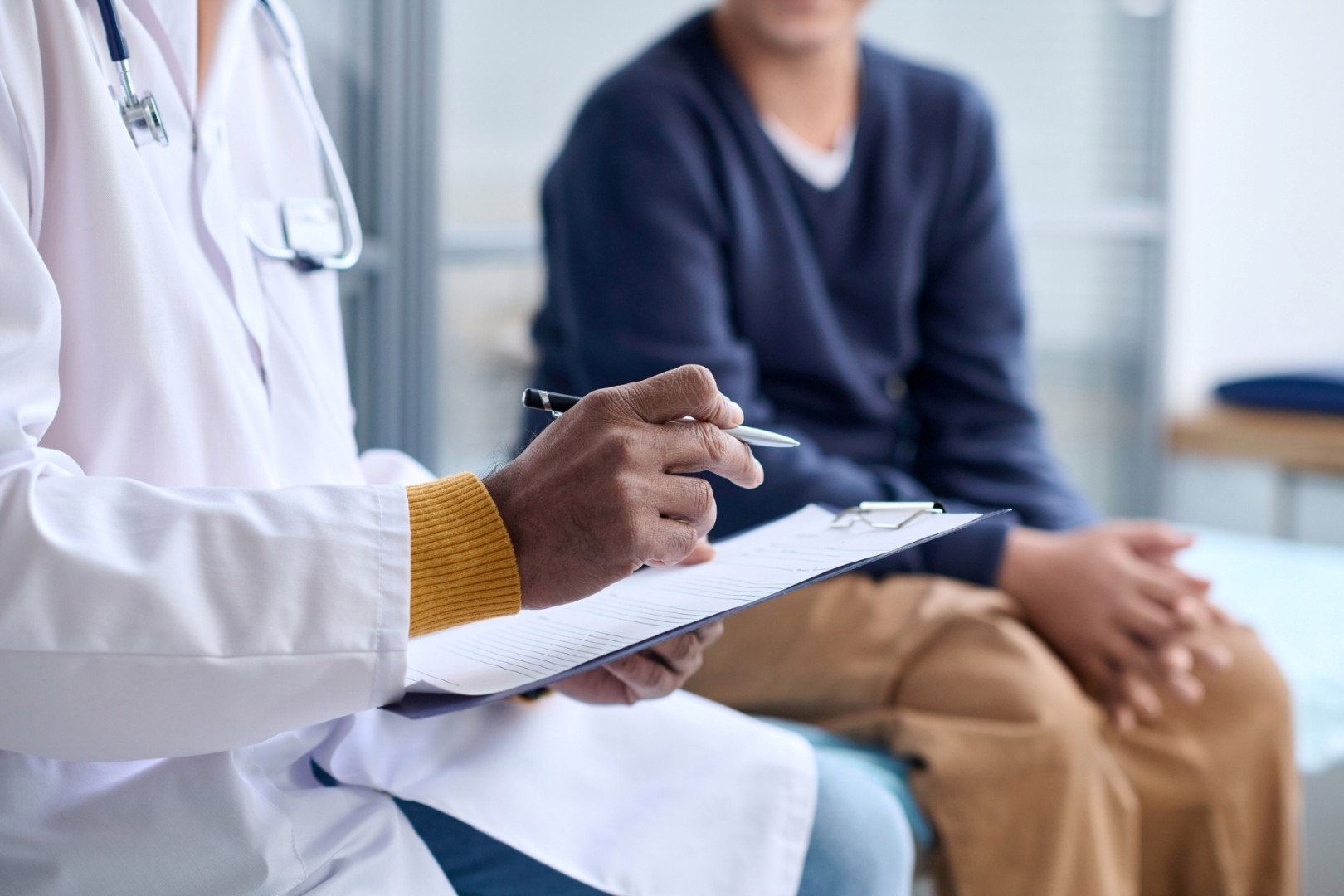 Physician writes on a clipboard and talks with a patient. 