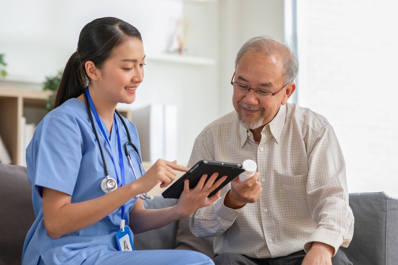 Physician talks with a patient as they look at a device. 