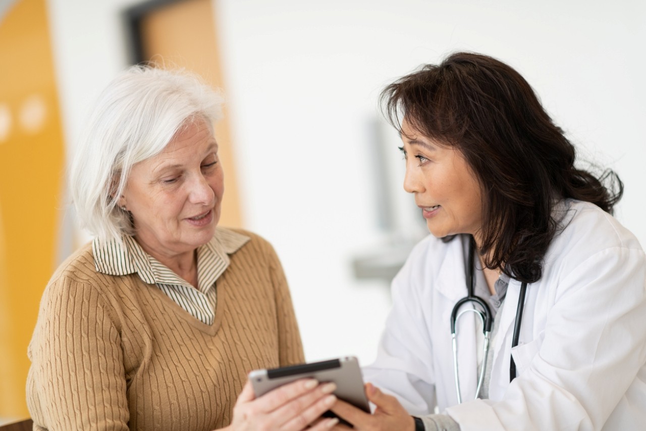 Patient and physician talk while looking at a device. 