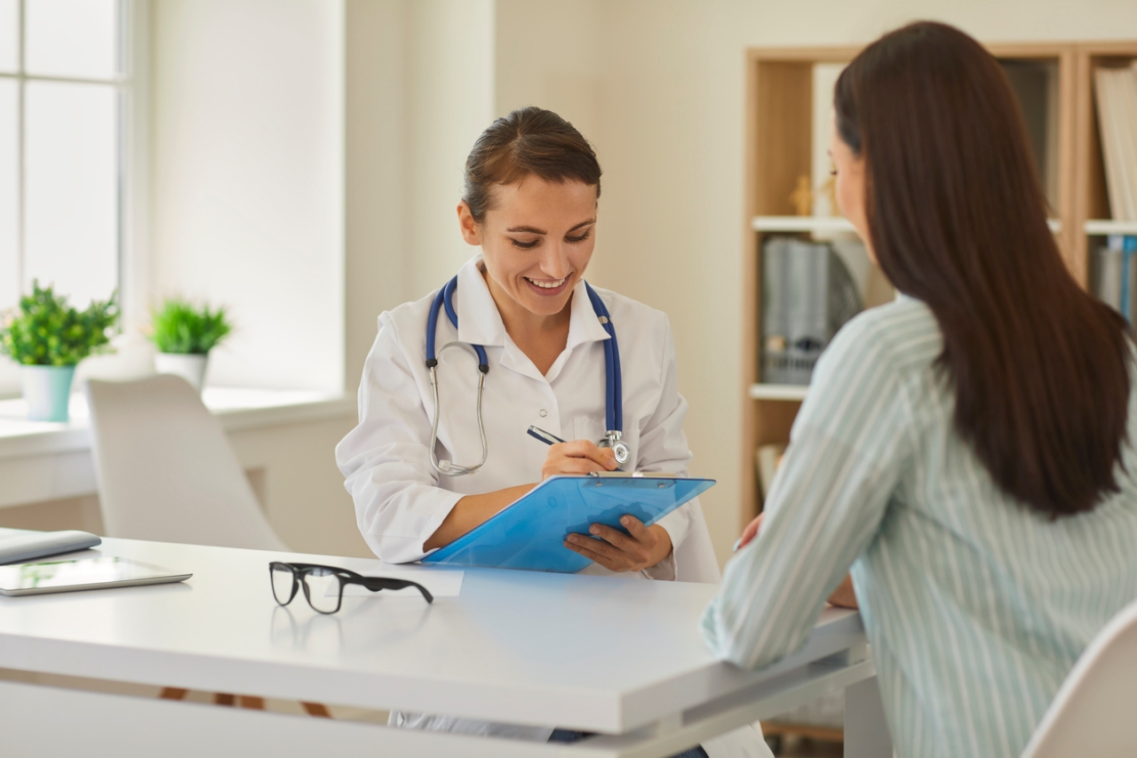 Physician talks with a patient while writing on a clipboard. 