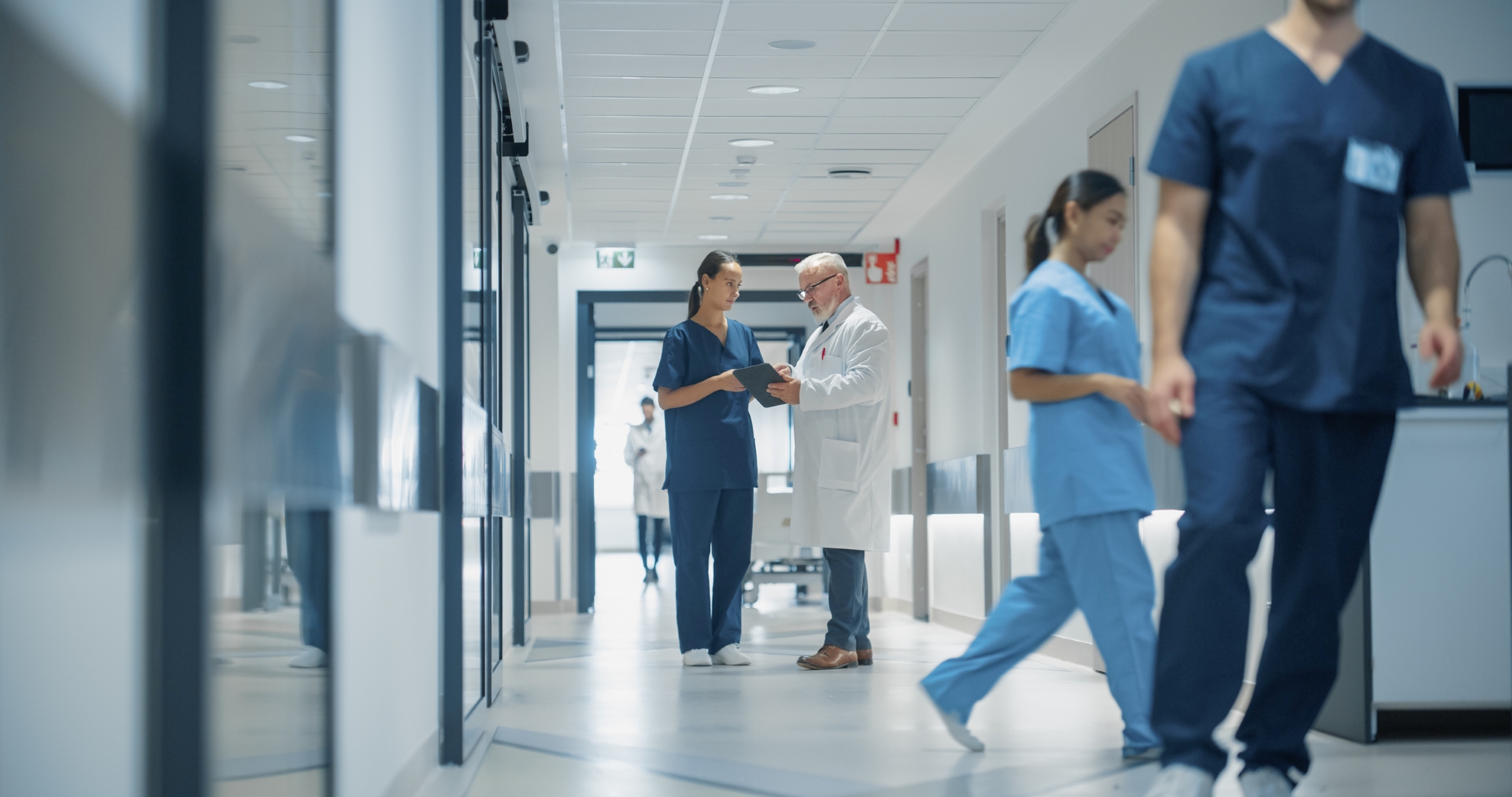 Physicians walk and talk in a hallway. 