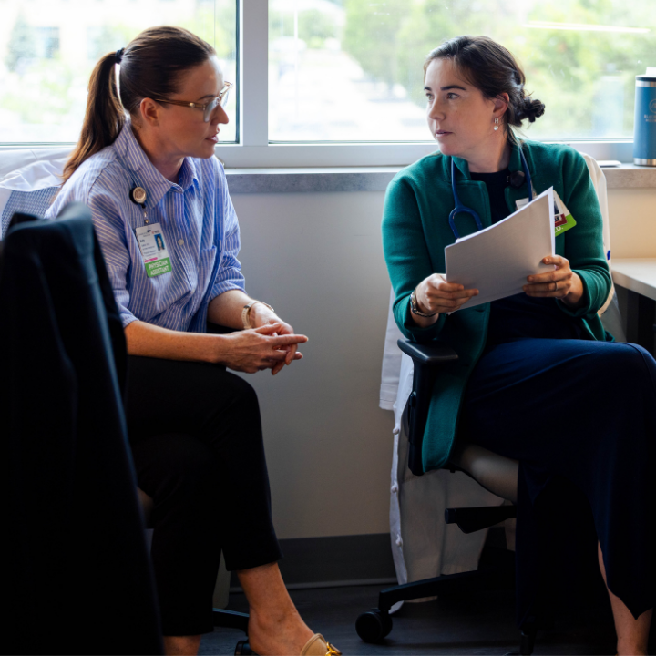 Two medical professionals talk in an office setting. 