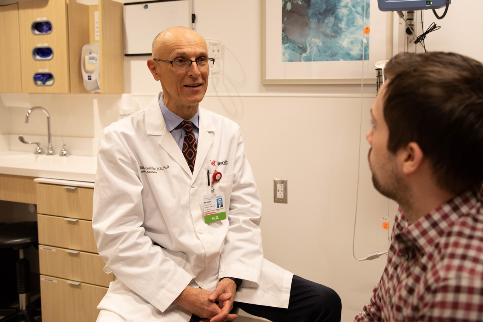 Physician meets with young patient in office during colorectal cancer appointment at UC Cancer Center.