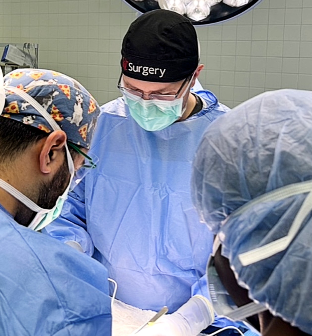 Physicians in scrubs and masks attend to a medical procedure. 