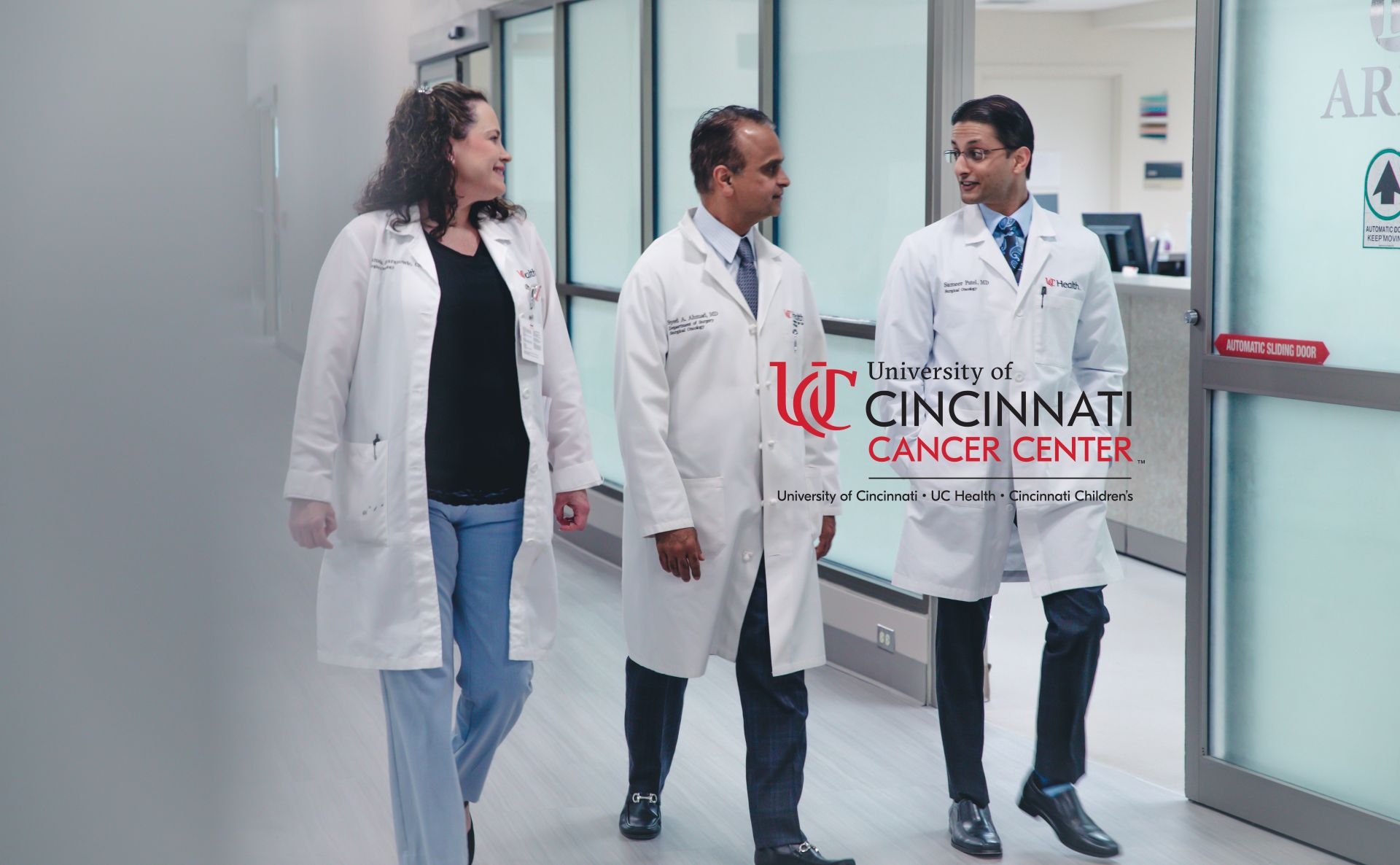Three physicians walk through hallway.
