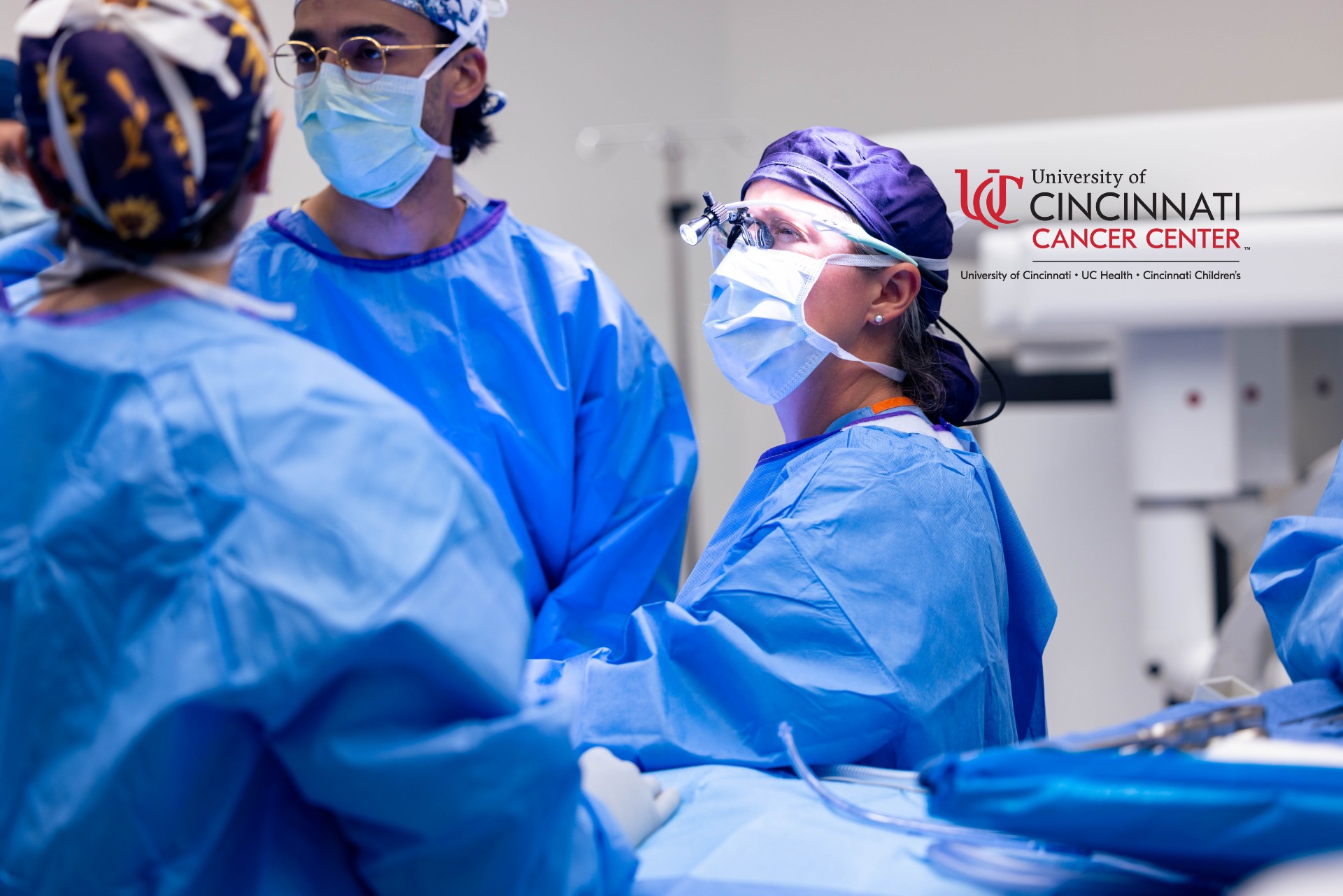 Physicians in scrubs and masks attend to a patient's medical procedure. 