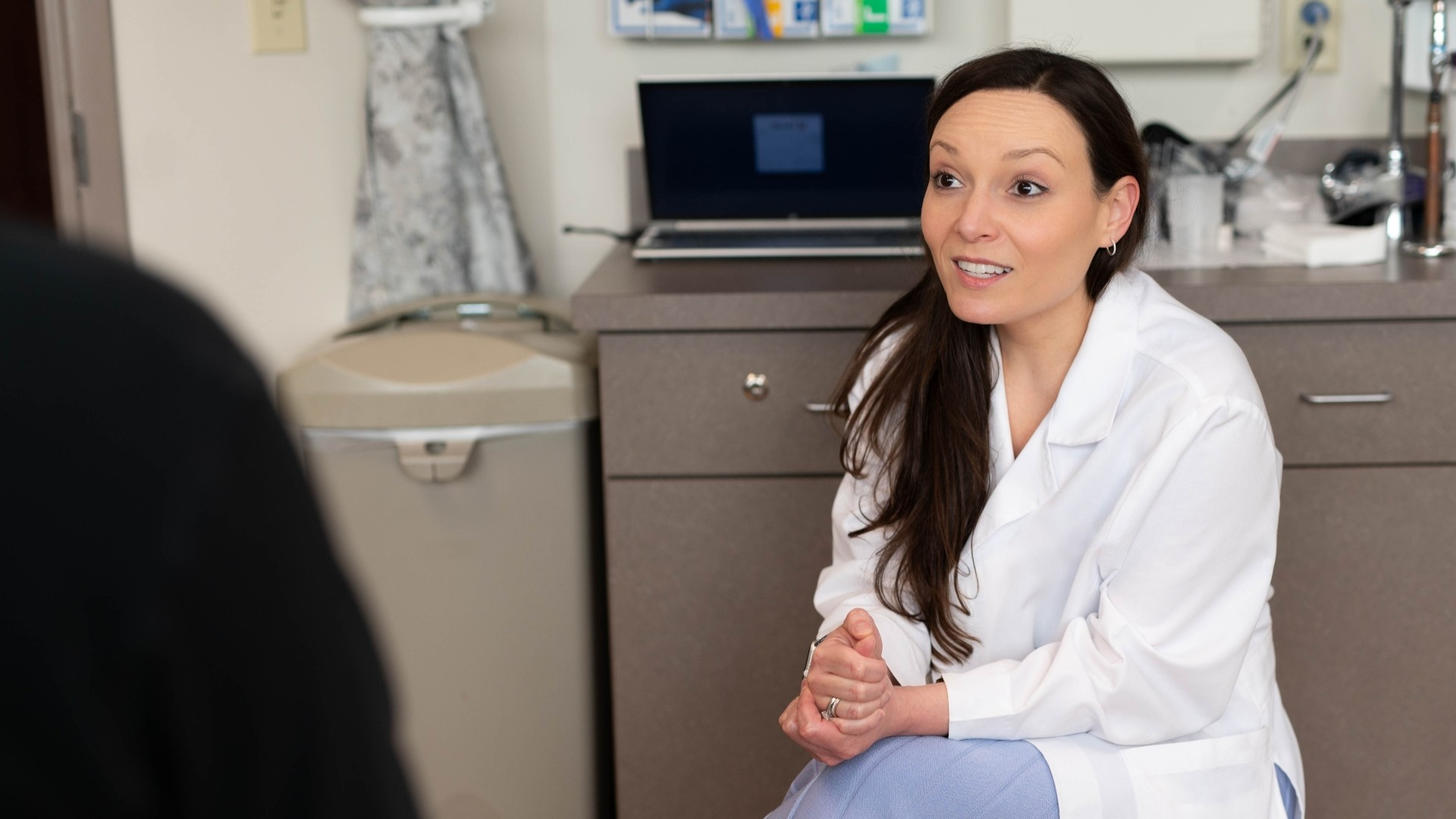 A physician talks with a patient in an exam room. 